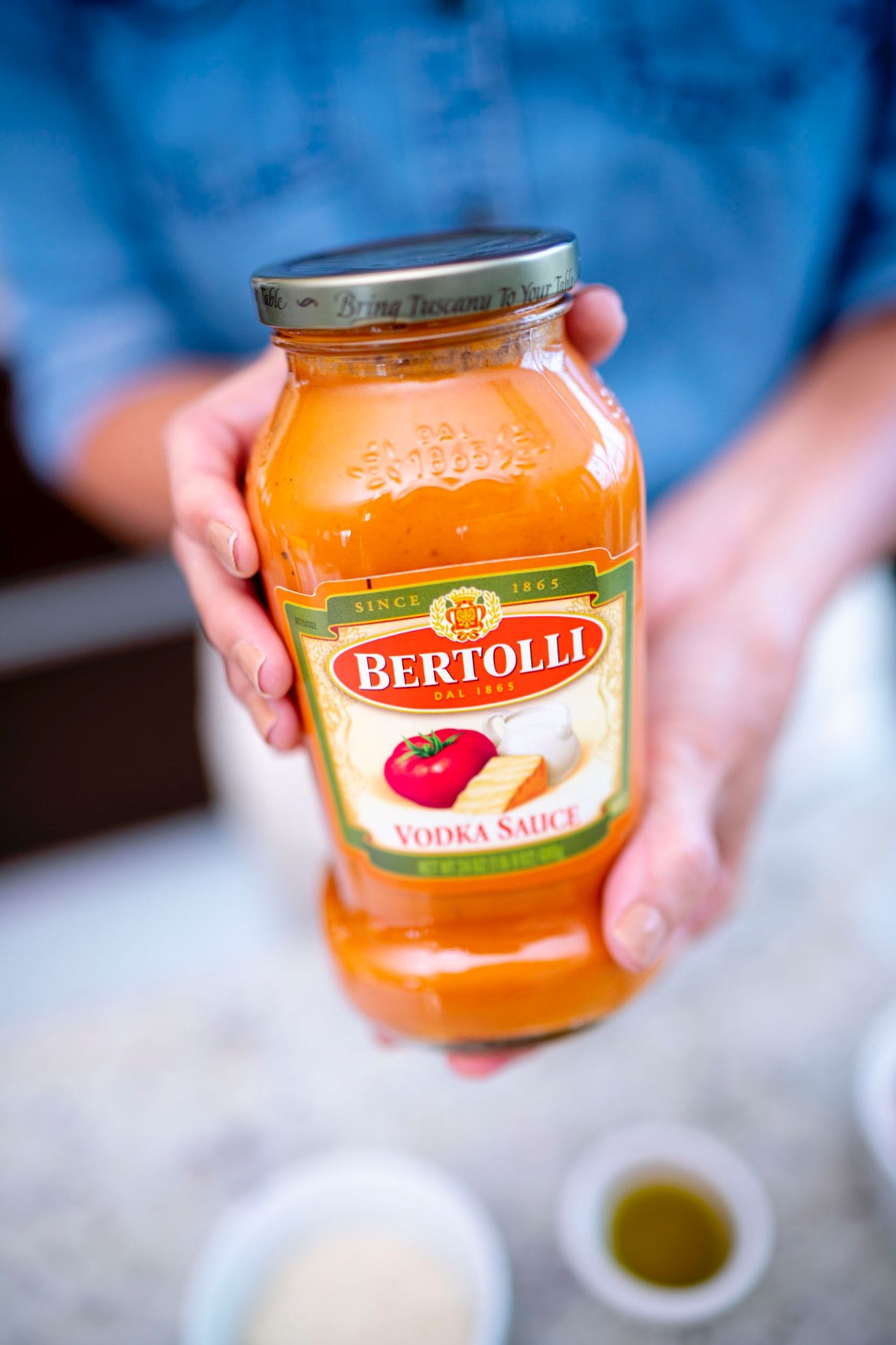 Mano sosteniendo un frasco de salsa Bertolli Vodka Sauce
