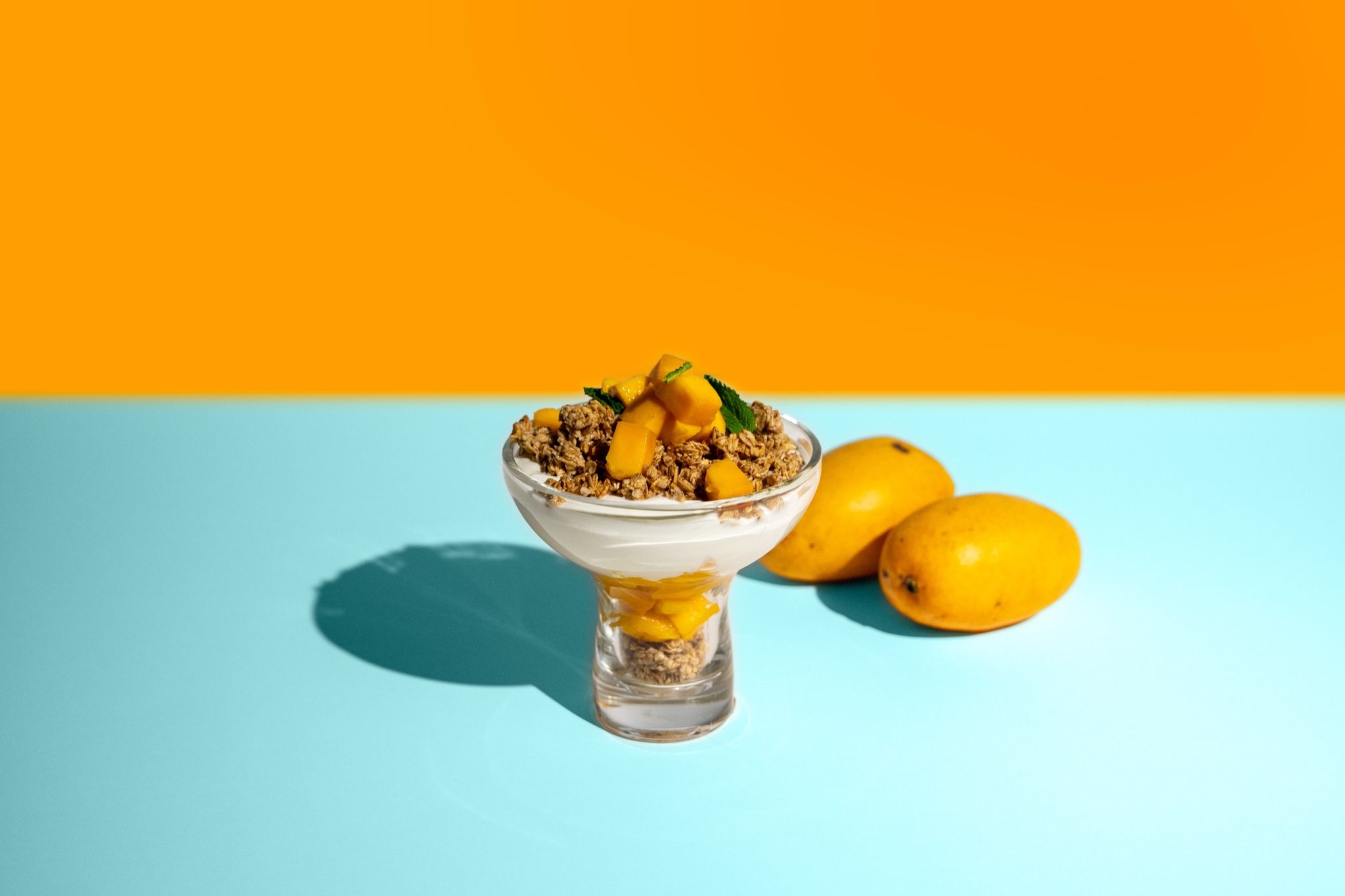 Parfait de mango sobre fondo naranja y azul