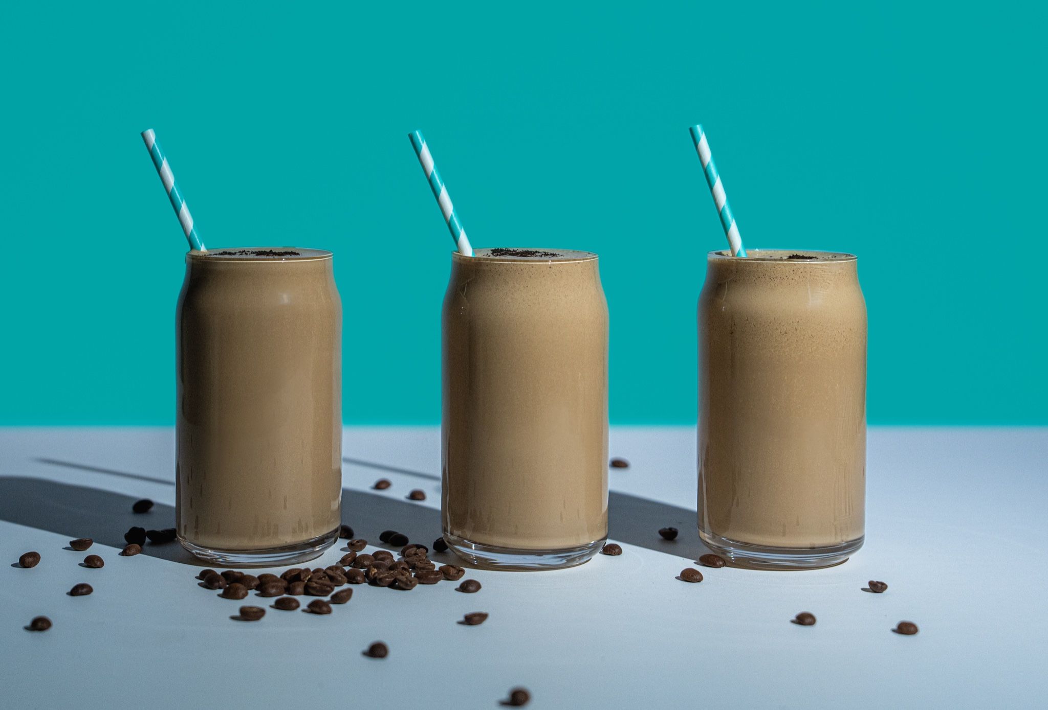 Tres frappés de café sobre fondo turquesa