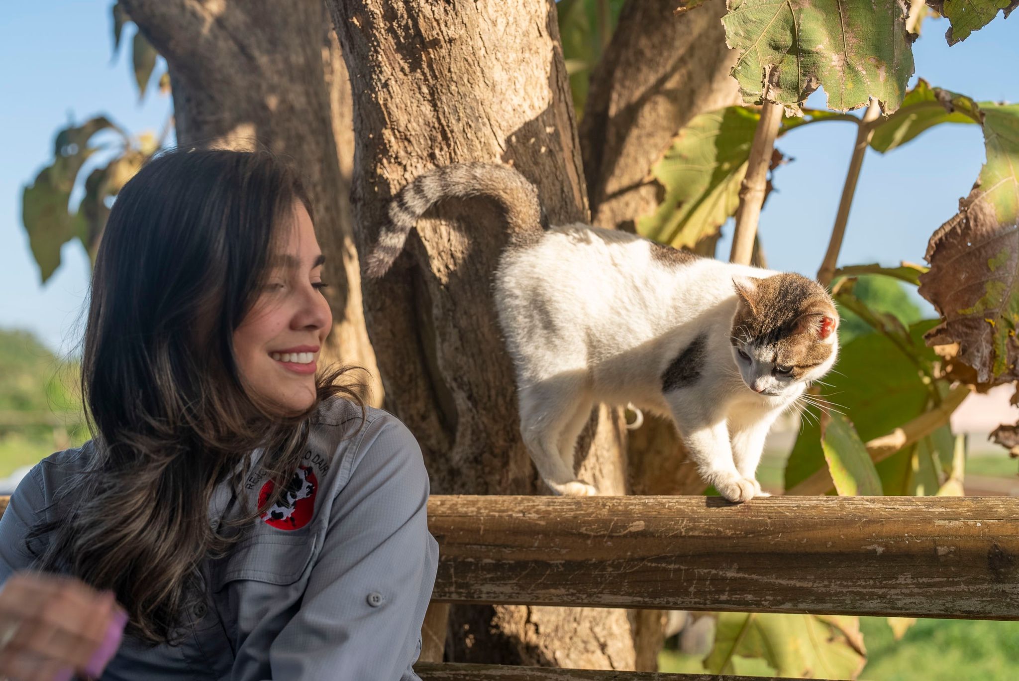 Integrante del equipo riendo junto a un gato subido a una verja